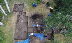 An aerial photo of a dug up foundation with assorted blue buckets, blue tarp and shovels